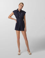 Woman wearing a dark denim romper on a plain background