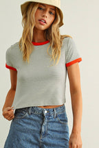 Woman wearing a striped shirt with red trim and denim pants on a plain background