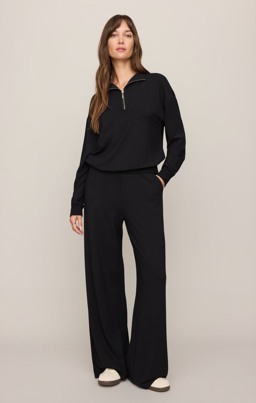 Woman wearing a black outfit with a high collar on a beige background