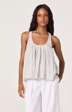 Woman wearing a striped tank top and white pants on a plain background