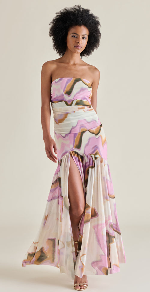 Woman wearing a strapless floral dress with a high slit on a plain background