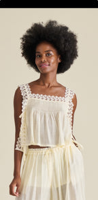 Woman wearing a white lace-trimmed top and skirt against a plain background