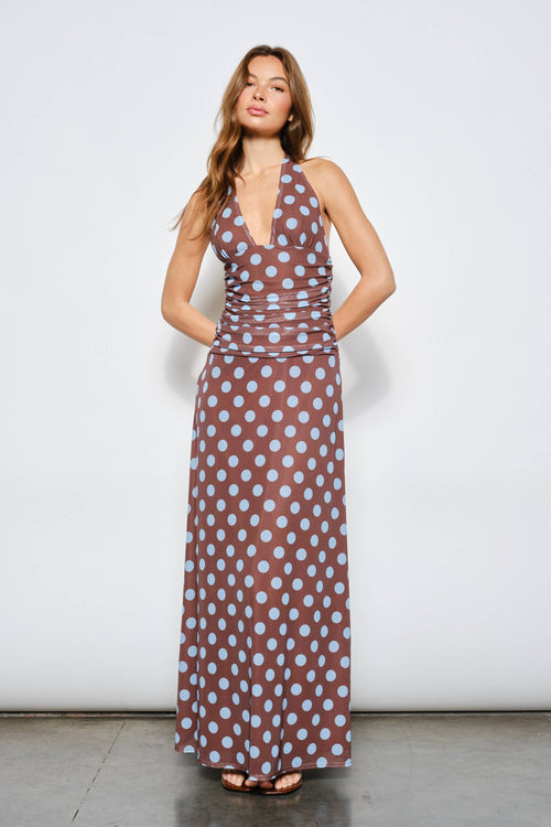 Woman wearing a brown dress with white polka dots against a white background