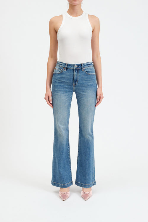 Person wearing a white sleeveless top and blue flared jeans on a white background