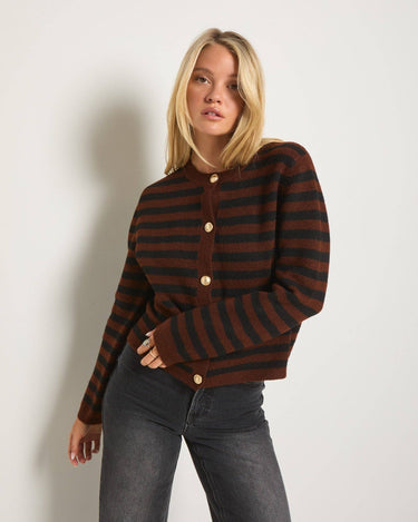 Woman wearing a brown and black striped sweater against a plain background
