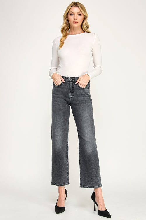 Woman wearing a white long-sleeve top and gray jeans on a white background