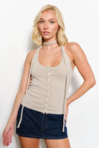 Woman wearing a beige halter top and denim shorts on a white background