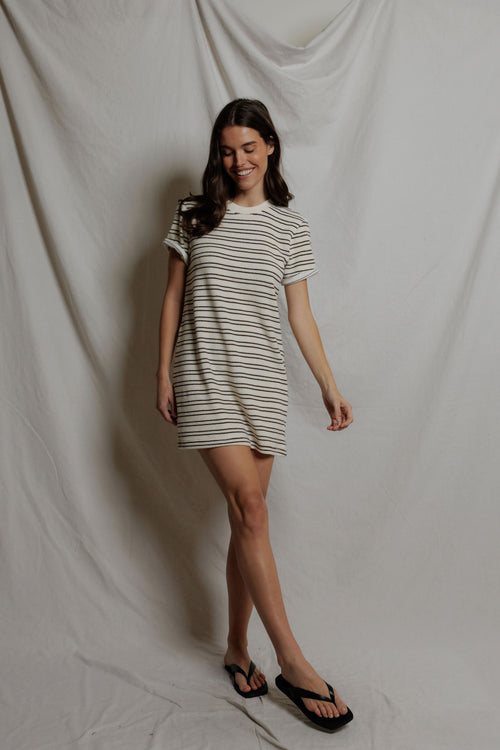 Woman wearing a striped dress standing against a plain background