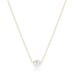 Gold necklace with a single pearl pendant on a white background