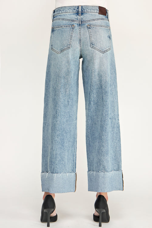 Light wash blue denim cropped wide-leg jeans with rolled cuffs, shown from the back on a model wearing black high heels against a plain white background.