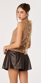 Woman wearing a brown sleeveless top with lace details and a black skirt on a white background