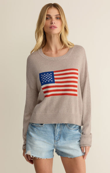 Woman wearing a sweater with an American flag design on a beige background