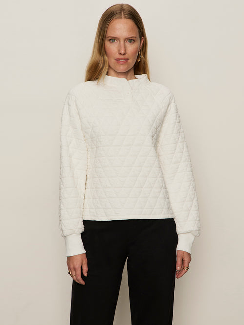 Woman wearing a white quilted jacket against a plain background