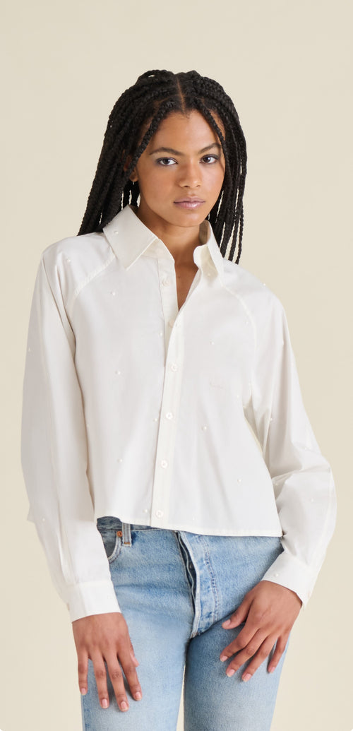 Woman wearing a white blouse and blue jeans against a beige background