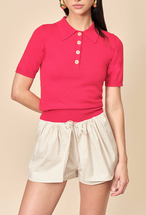 Person wearing a red polo shirt and white shorts on a beige background
