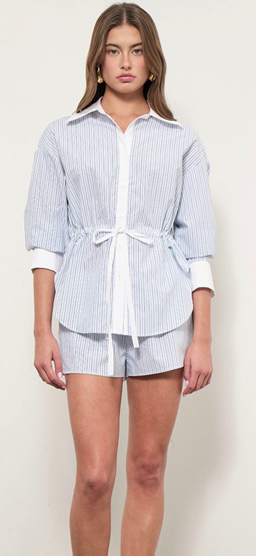Woman wearing a blue and white striped shirt and shorts on a plain background