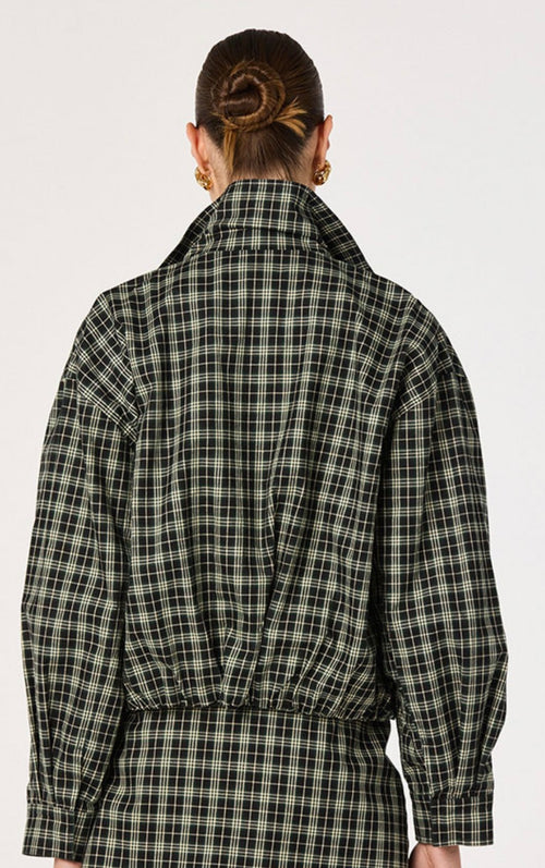 A model shown from the back wearing a black and white plaid long-sleeve shirt with a high collar and gathered waist details, set against a plain light gray background.