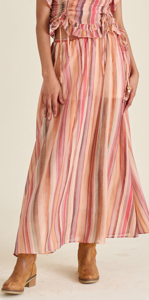 Person wearing a long, striped dress with a neutral background