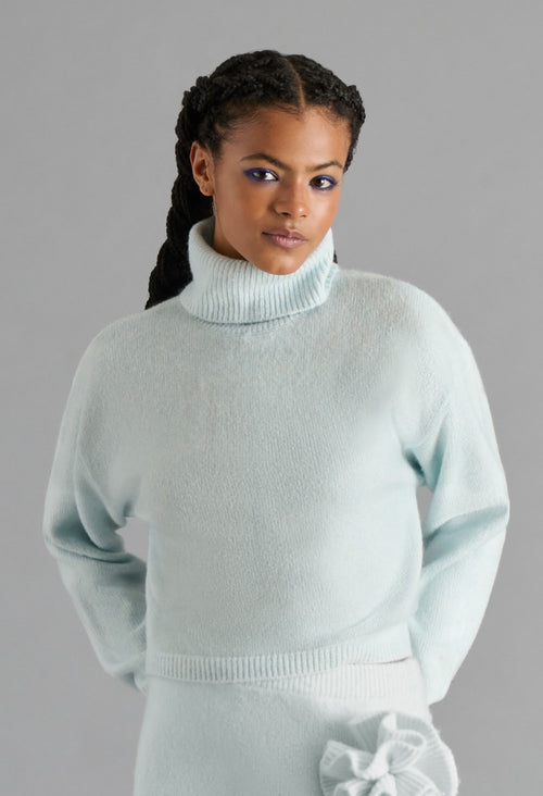 Woman wearing a light blue sweater against a gray background