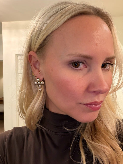 Close-up of a person wearing pearl earrings with a neutral background
