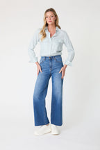woman wearing jeans and a shirt against a neutral background 
